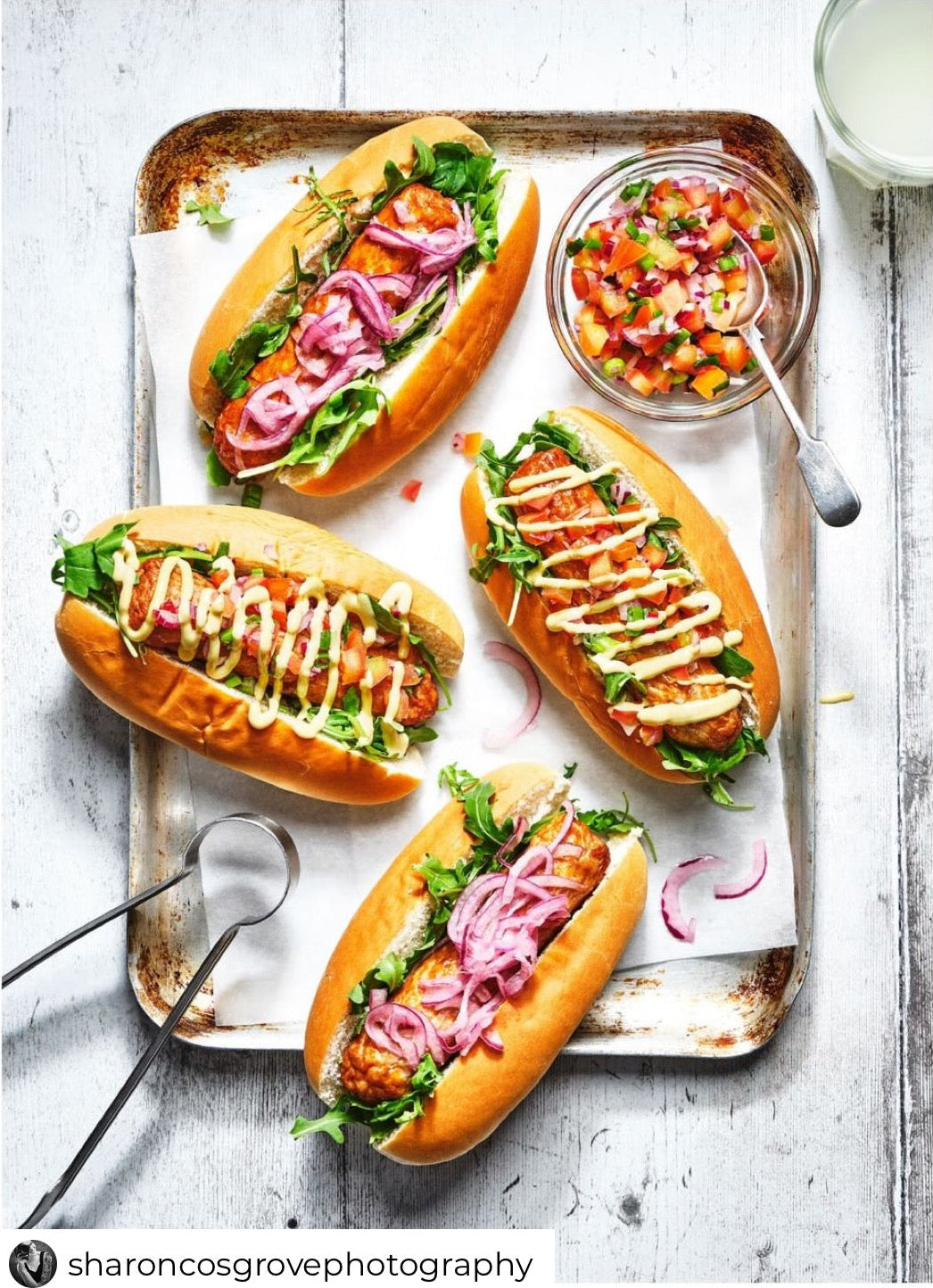 A white wood-effect vinyl backdrop with vertical planks with a flat lay of hotdogs.