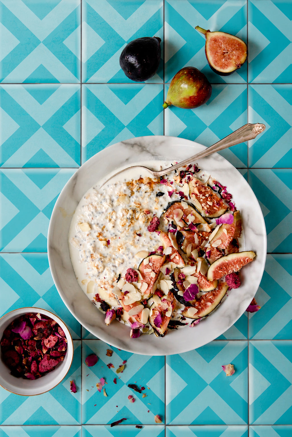 Oatmeal with figs and dried flowers sprinkles on a turquoise graphic tile-effect vinyl photography backdrop