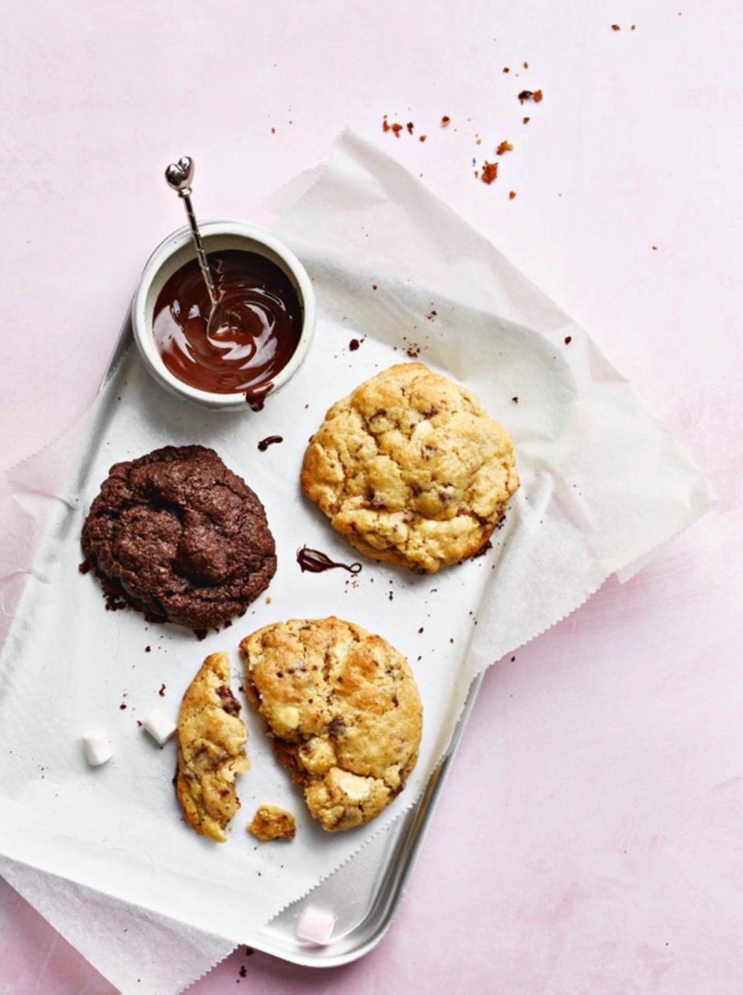 Flat lay of homemade chocolate cookies styled on a pale rose pink vinyl photography backdrop.