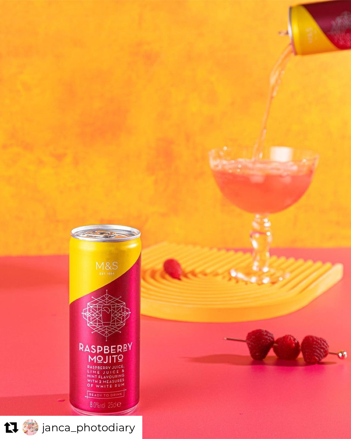 Raspberry Mojito being poured against a orange backdrop