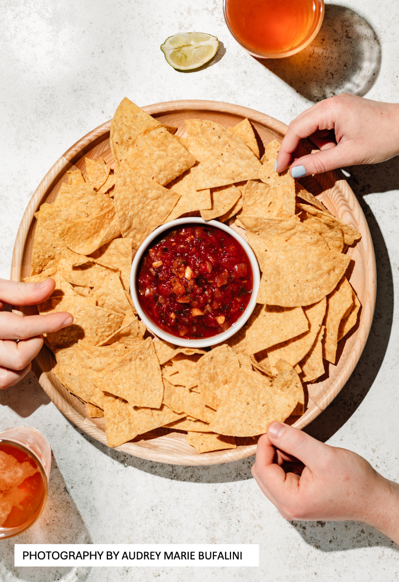 Top down shot of tortilla and dips with hands styled on a mottled white vinyl photography backdrop