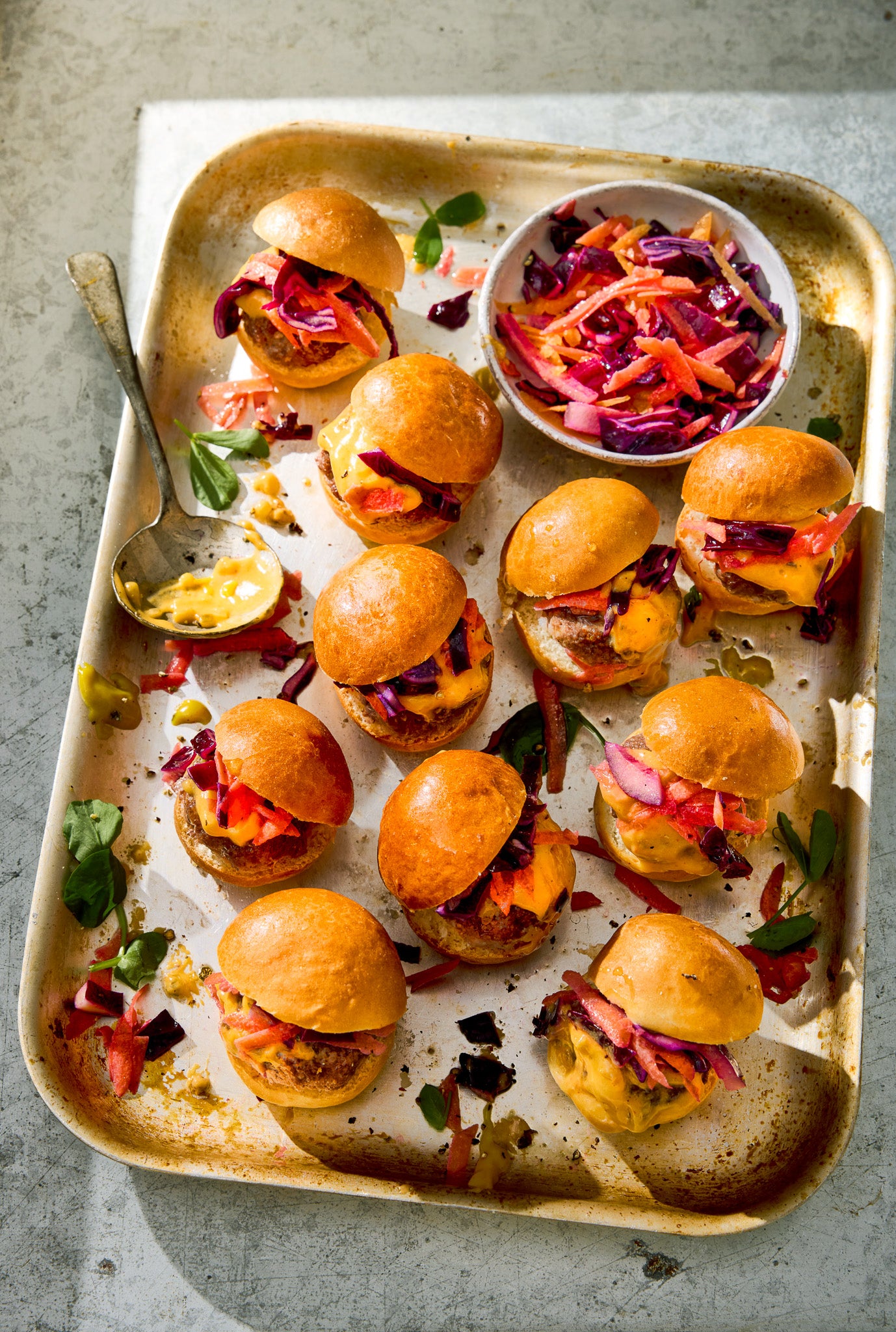 Small burgers on a metal tray with coleslaw