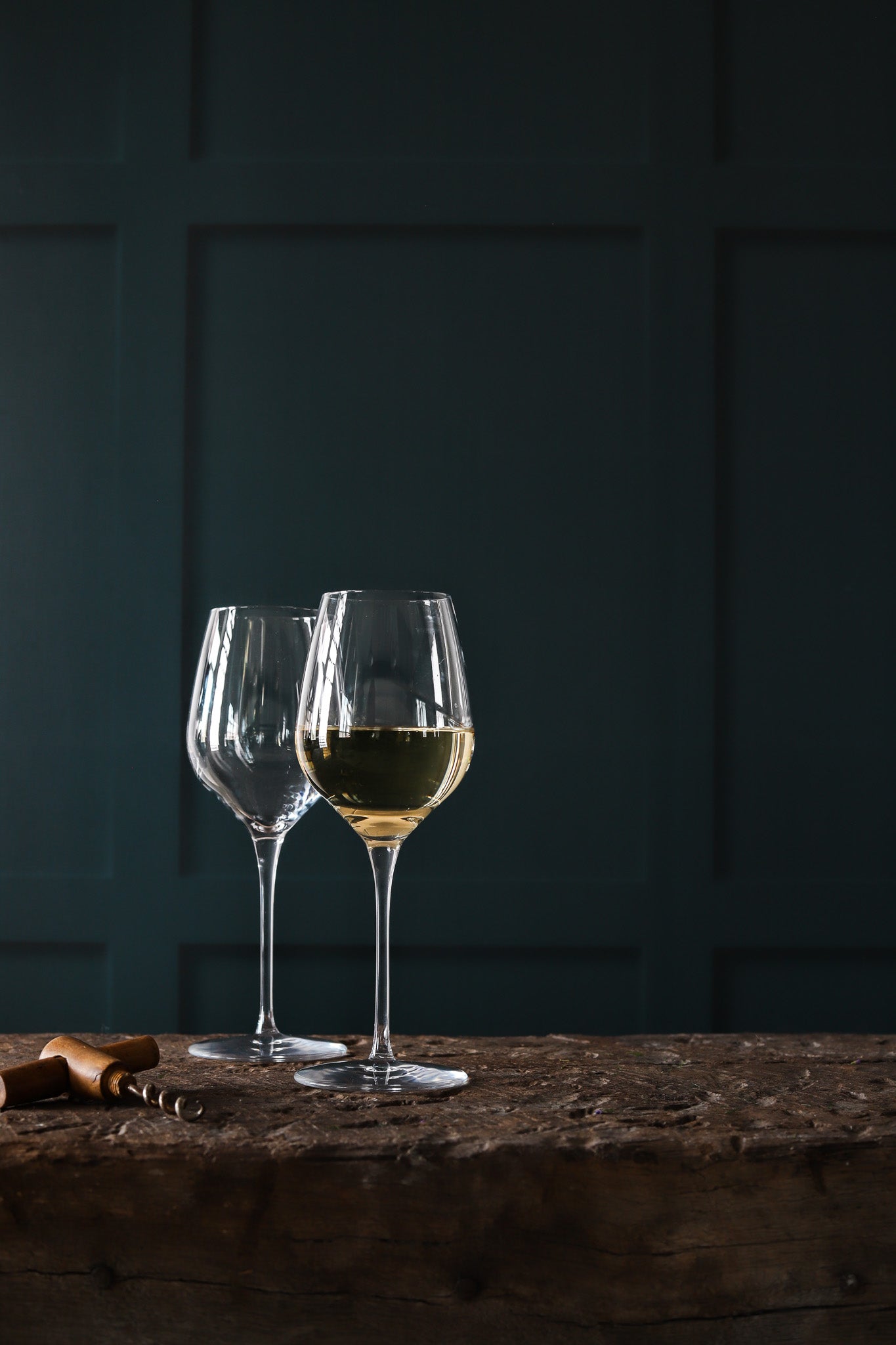Dark green panelled wall effect photography backdrop with glasses of white wine in the foreground