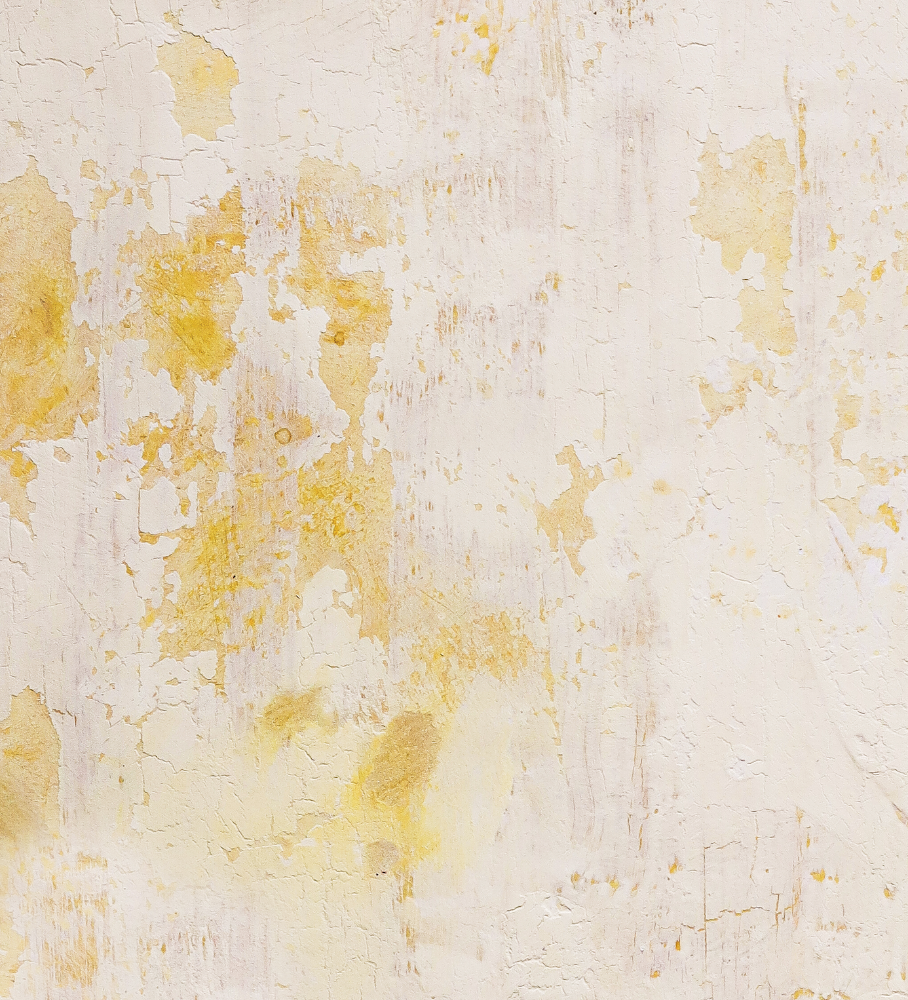 A close up of a crackled yellow paint effect photography backdrop with flaky texture revealing strong yellows under a buttery top.