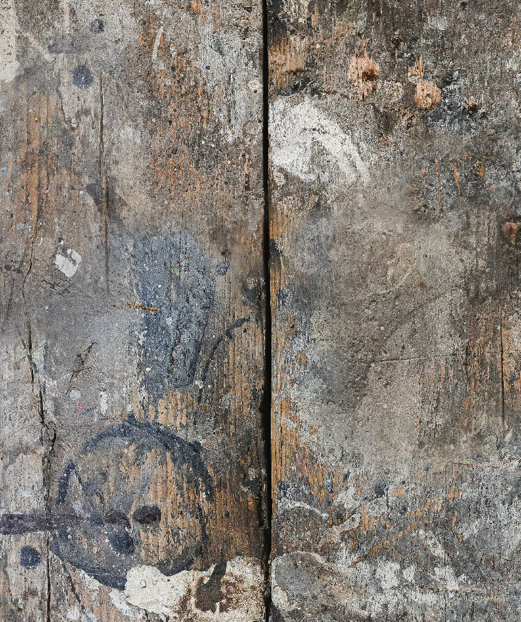 Close up of a rustic photography backdrop featuring a distressed wood effect with paint drips and various marks making it look like an old workbench.