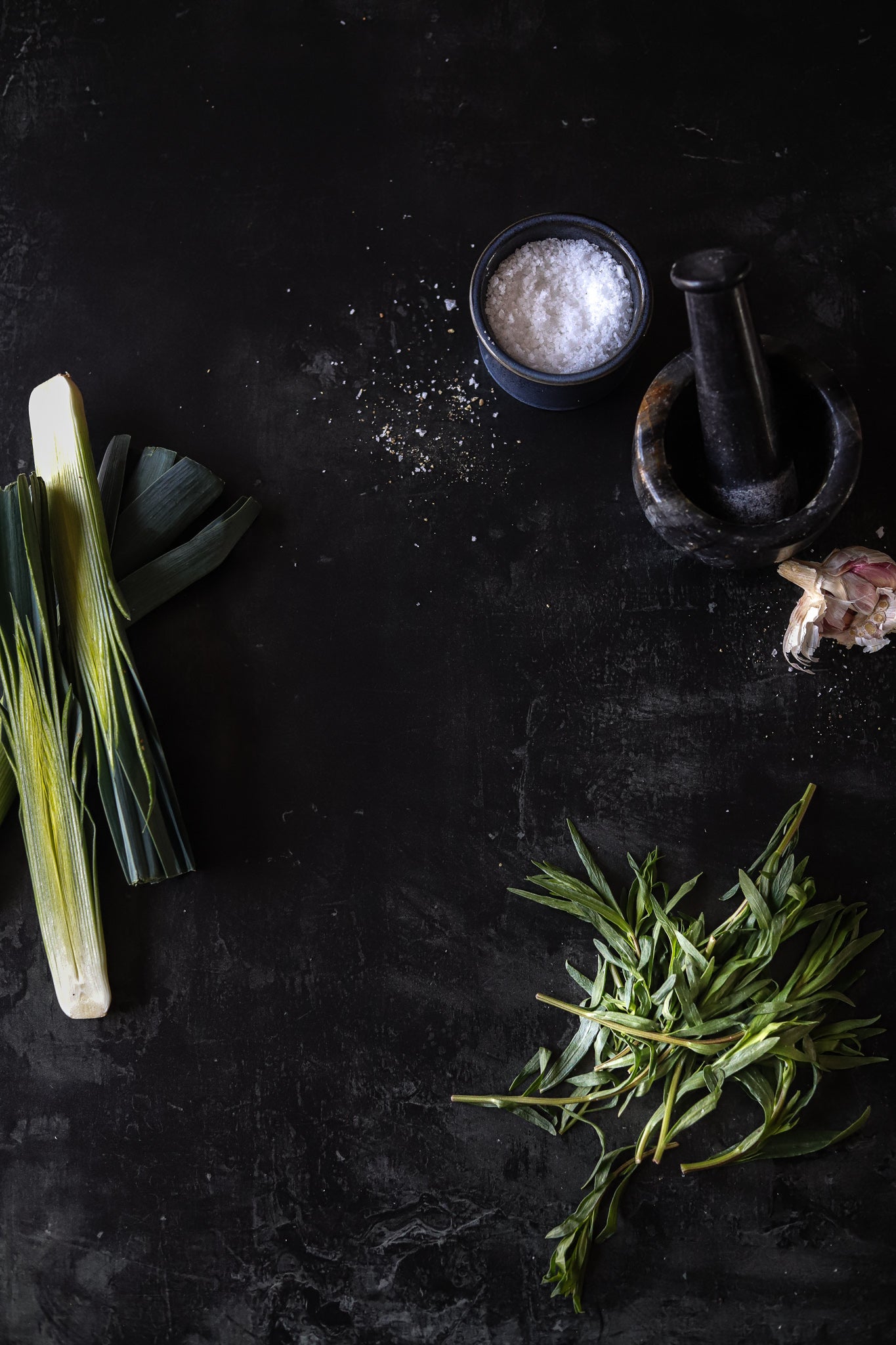 A black vinyl photography backdrop with a hand-painted effect and subtle slate-like texture, styled with a flat lay of salt and herbs.