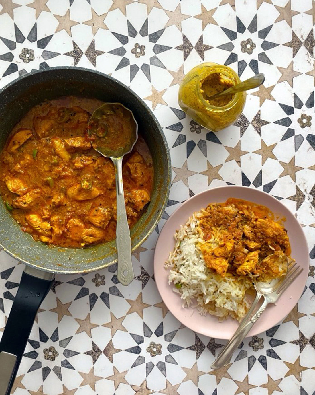 Pan of chicken curry shot on a geometric tile photography backdrop