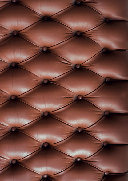 A close-up image of a tan leather effect photography backdrop with button details, resembling a Chesterfield sofa.