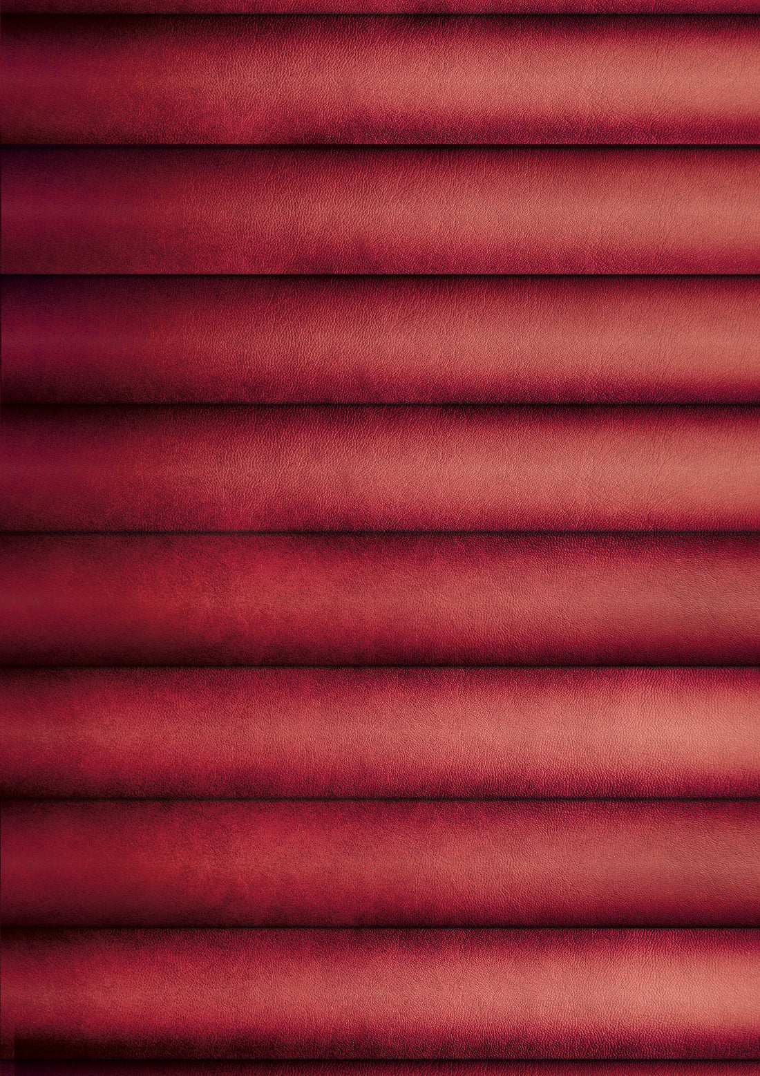 A close-up view of a red ribbed leather effect photography backdrop with highlights and shadows captured from an American diner upholstered booth.