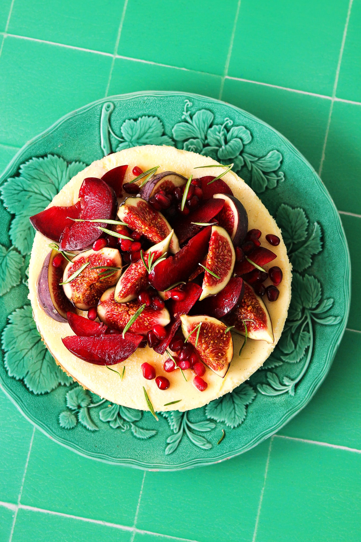 A fig cheesecake on an Antique Majolica plate styled on a jade green vinyl photography backdrop with a crackled vintage tile effect.