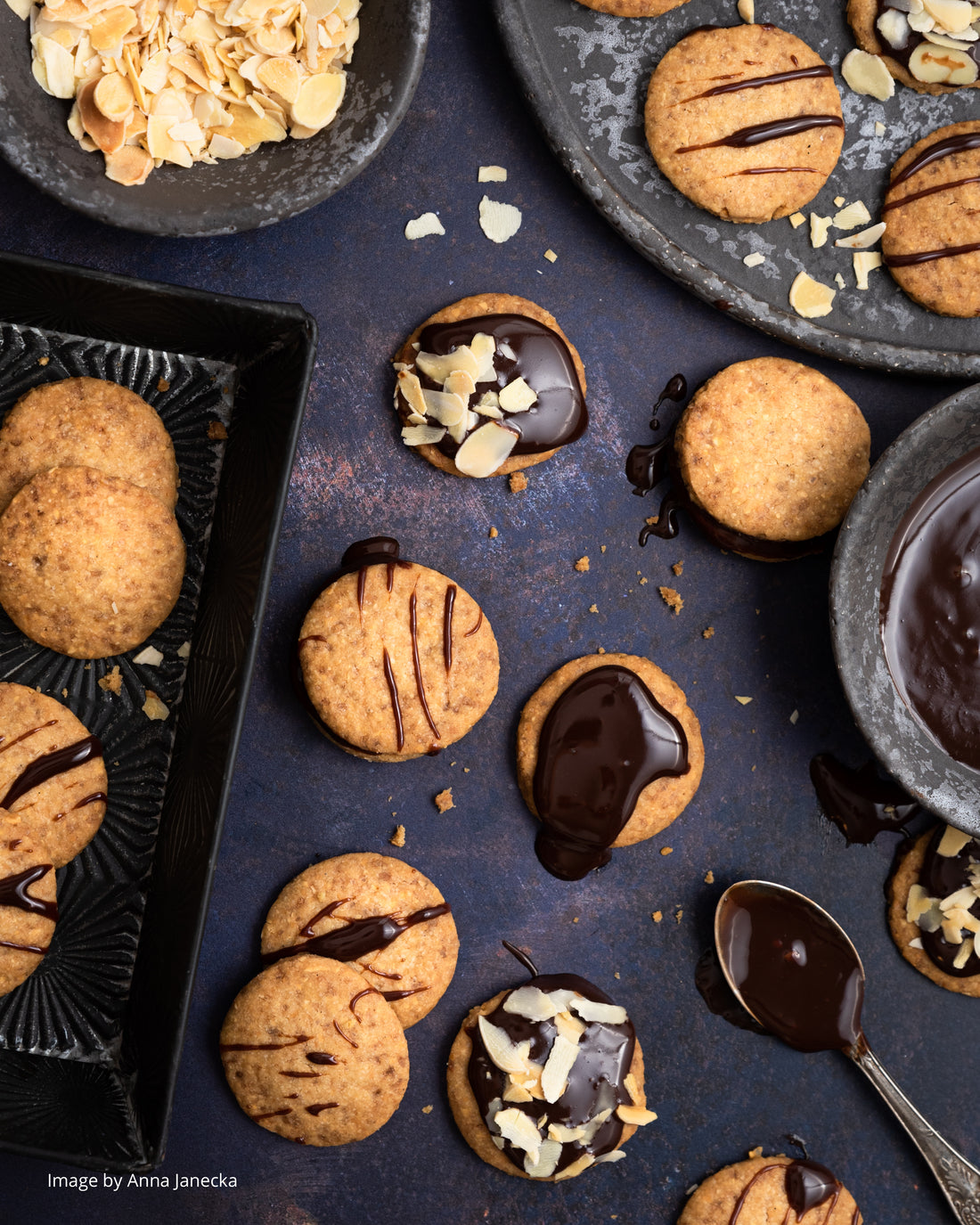 A flat lay of homemade biscuits styled on a dark blue vinyl photography backdrop with a warm rust effect showcasing varying shades of navy blue, taupe and rust highlights.