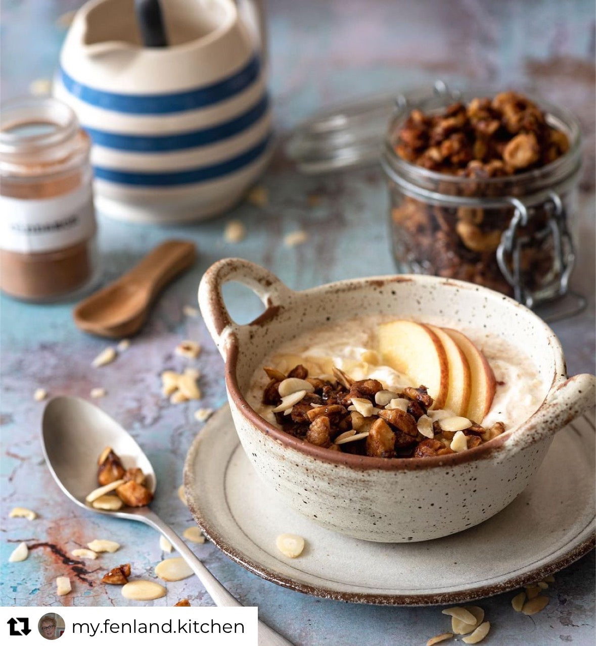 A healthy breakfast bowl styled on a vinyl photography backdrop with a distressed paint effect with varying shades of green, grey and blue.