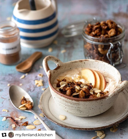 A healthy breakfast bowl styled on a vinyl photography backdrop with a distressed paint effect with varying shades of green, grey and blue.