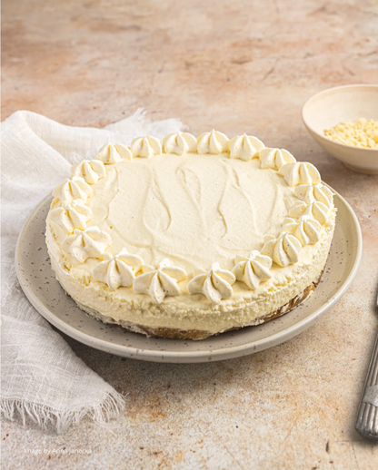 White chocolate cheesecake styled against a mottled warm beige vinyl photography backdrop.