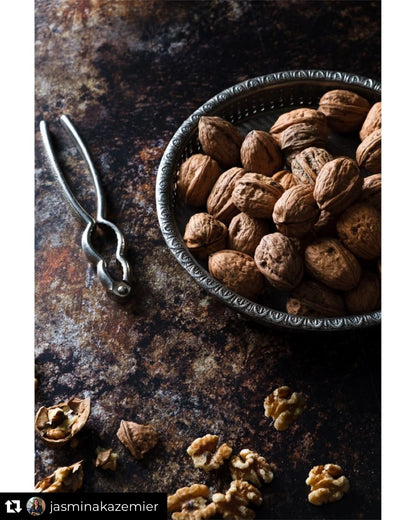 Flat lay of walnuts styled on a mottled brown vinyl photography backdrop with dark, umber tones and delicate rusted patches.