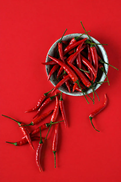 Red chili peppers in a bowl on a red photography background