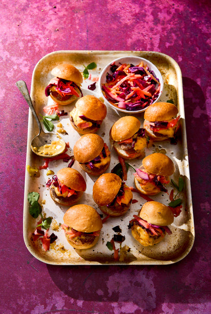 Tray of mini burgers styled on a striking textured deep pink paint effect photography backdrop.