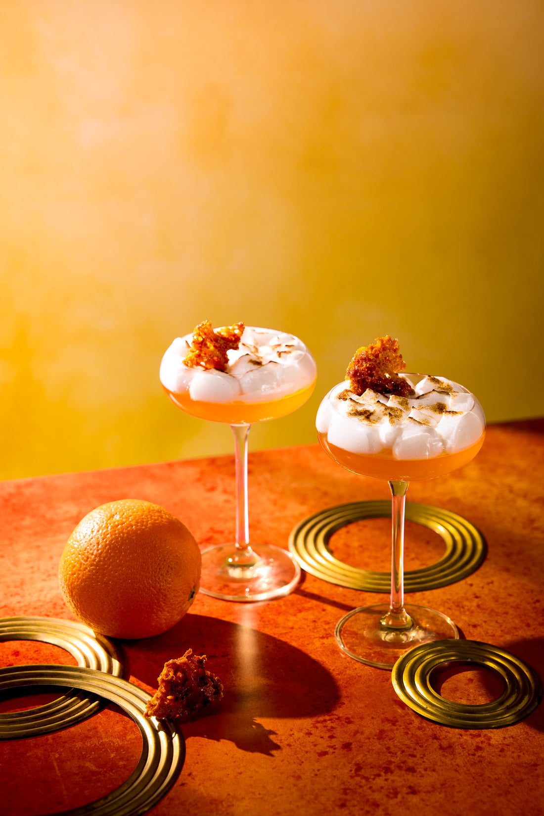 Bright orange cocktails against a hand-painted effect yellow vinyl photography backdrop with a soft gradient of paler and darker yellows.