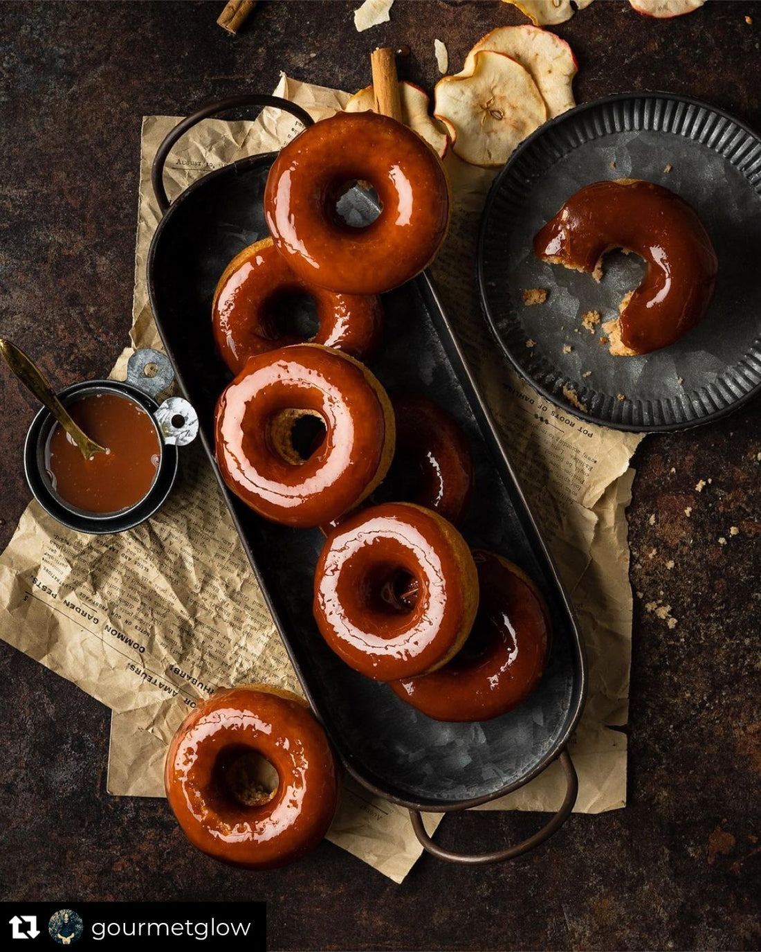 A flat lay of toffee donuts on a vintage tray styled on a vinyl photography backdrop with a cool brown mottled pattern.