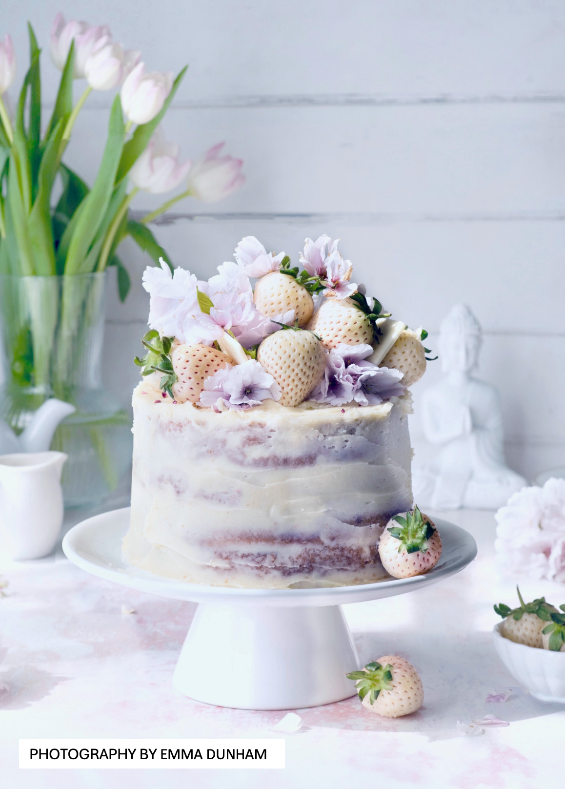 White strawberry cake on a light wood effect vinyl photography backdrop. Emma_Dunham_Photography