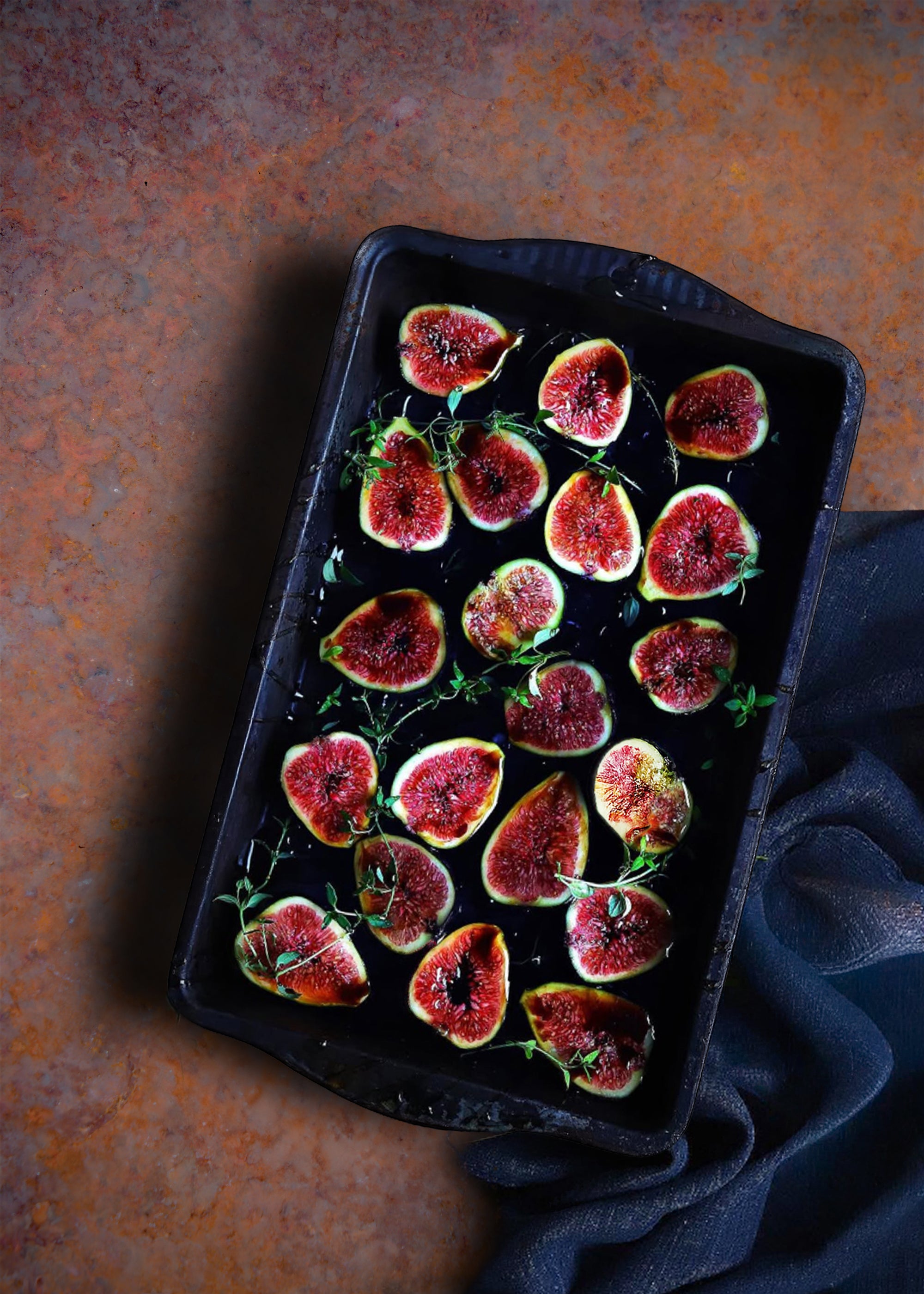 Roasted figs on a dark baking tray with a rustic background