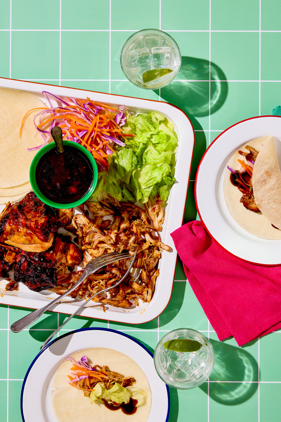 A pulled pork flat lay shot on a vinyl photography backdrop featuring a graphic tile effect in soft green with white grout lines.