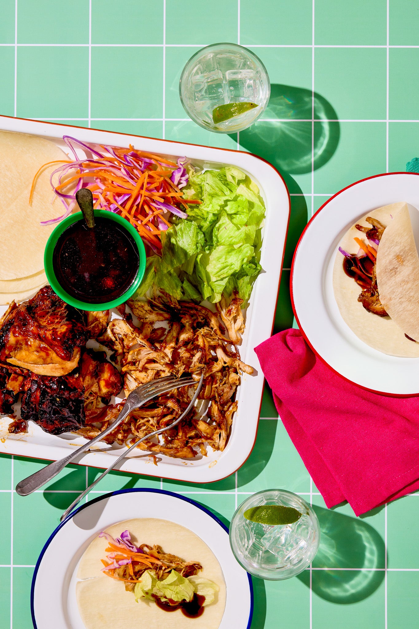 A pulled pork flat lay shot on a vinyl photography backdrop featuring a graphic tile effect in soft green with white grout lines.