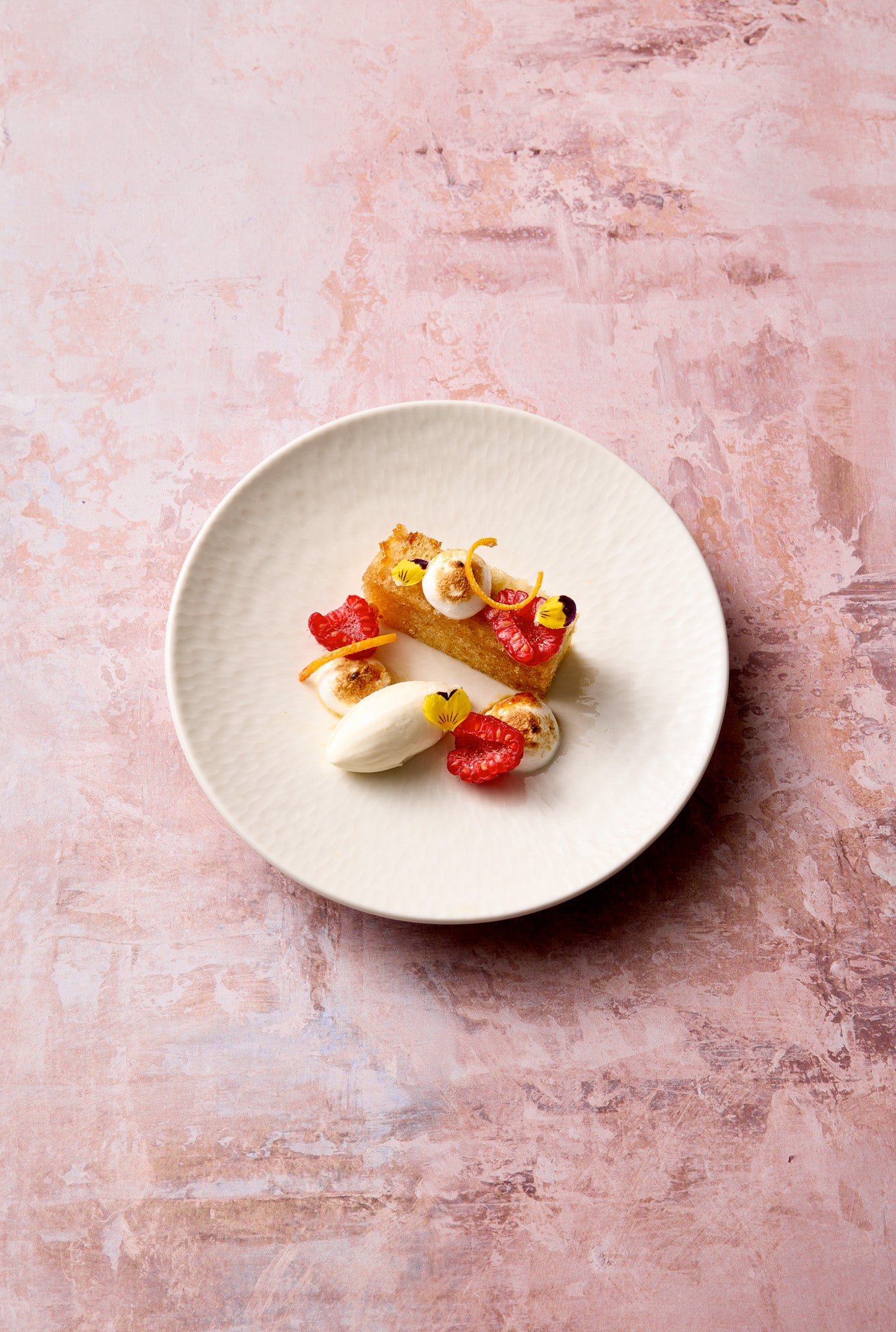 A plated minimalist dessert styled on a vinyl photography backdrop with a beige, brown, and orange layered painted effect.