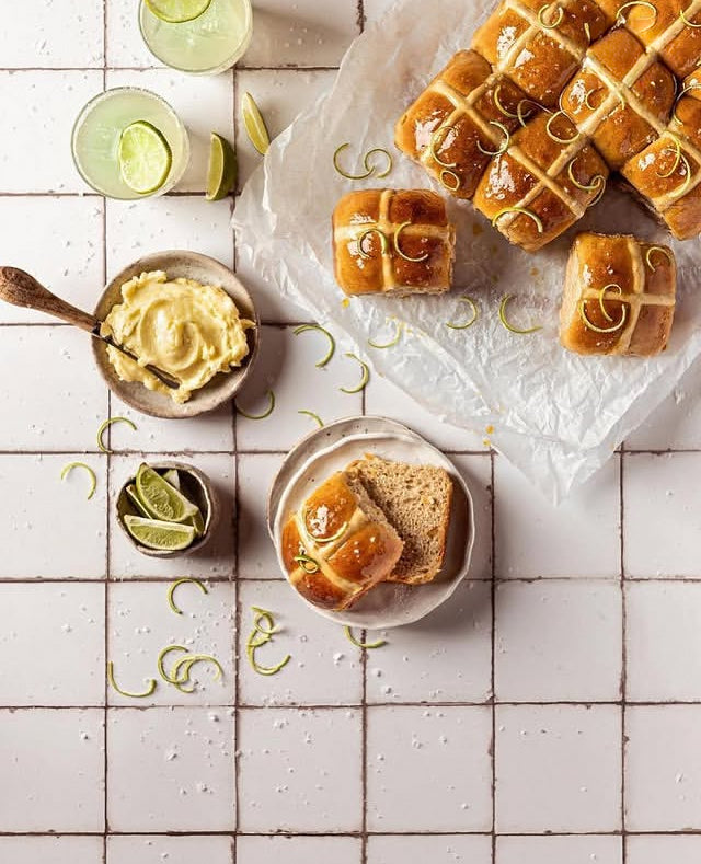 Flat lay of Margarita Hot Cross Buns styled on a white tile vinyl photography backdrop with a subtle grey grid lines and texture.