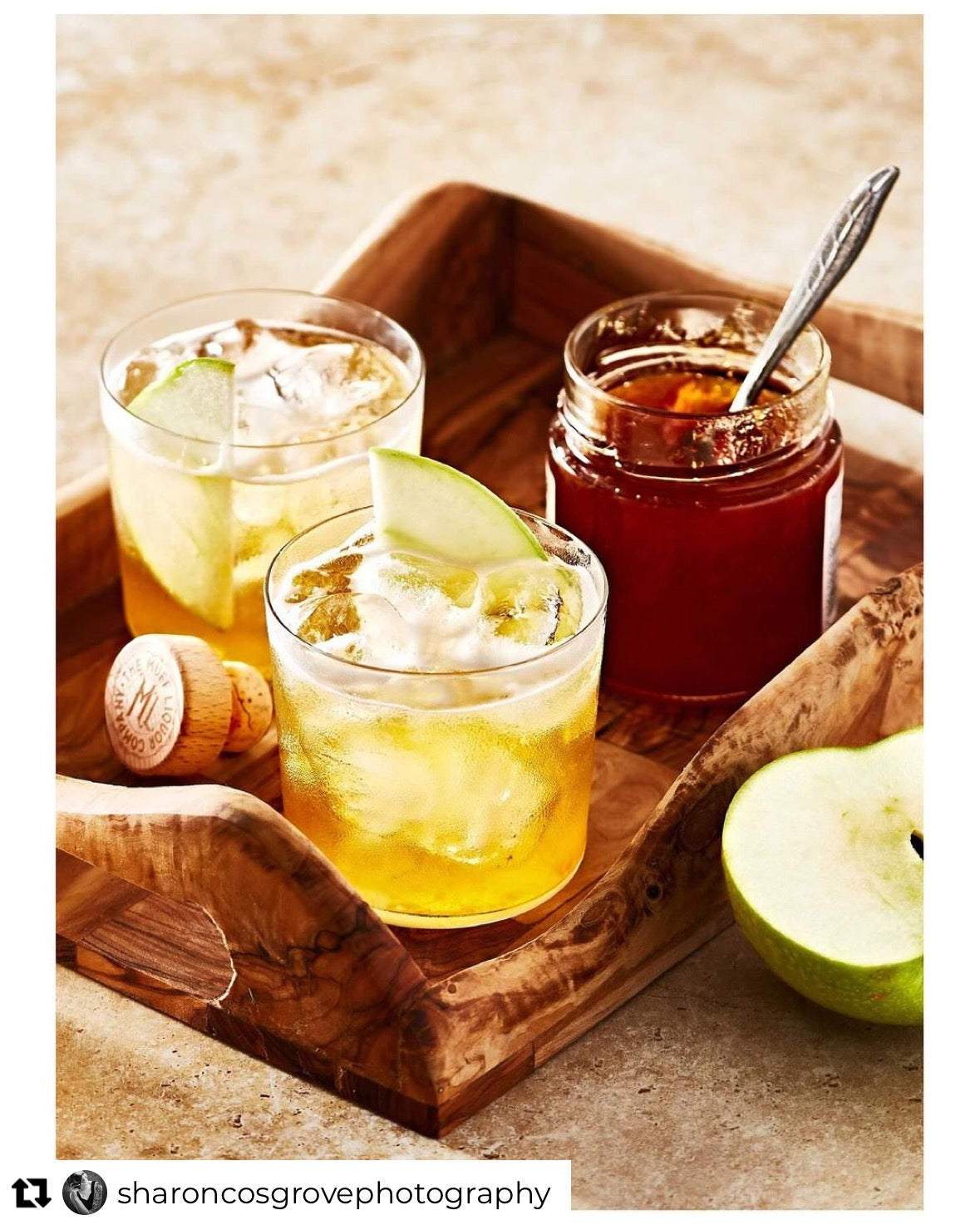 A travertine stone-effect photography backdrop with various shades of brown, cream, and yellow, with authentic stone fault lines and crevices, styled with two apple cocktails on a wooden tray.
