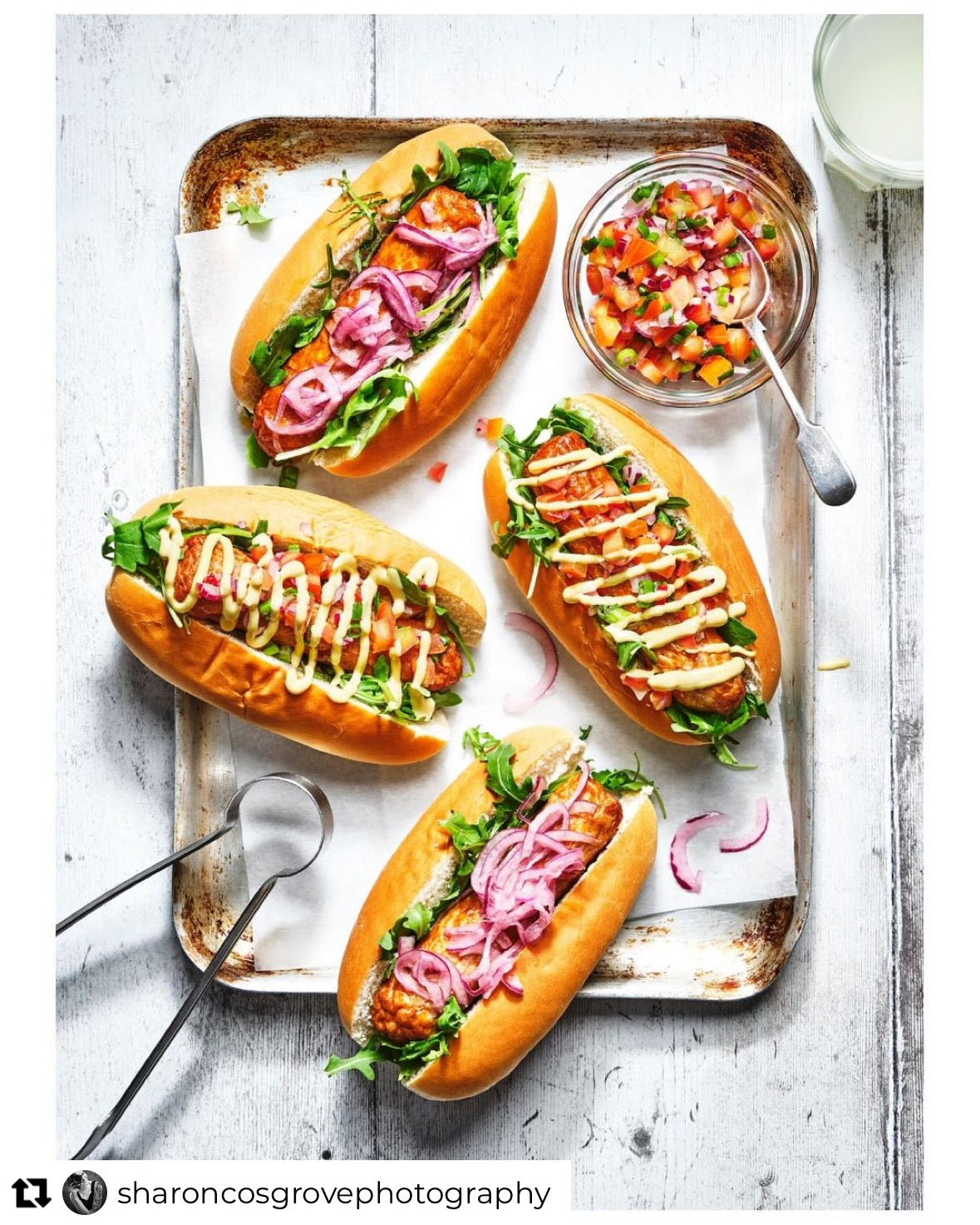A white wood-effect vinyl backdrop with vertical planks with a flat lay of hotdogs.