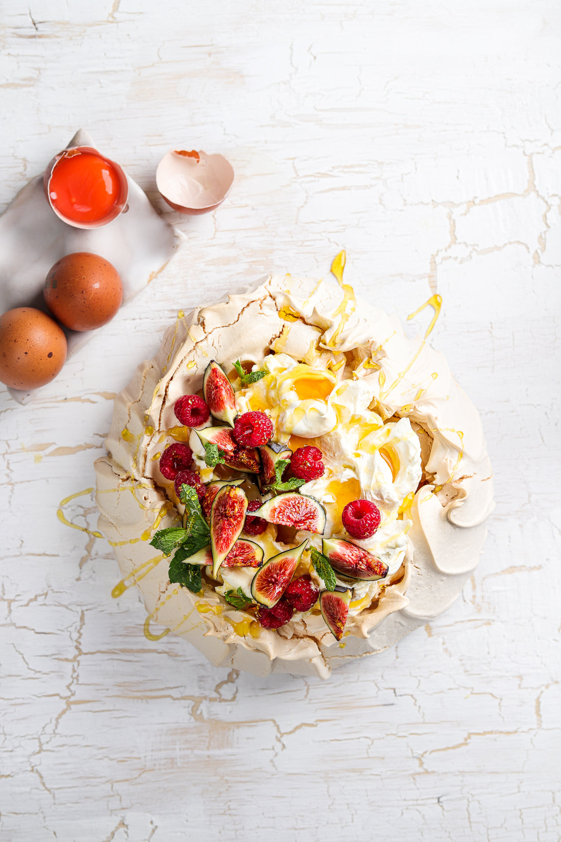 Flat lay of a handmade pavlova styled on a white rustic wood photography backdrop. 