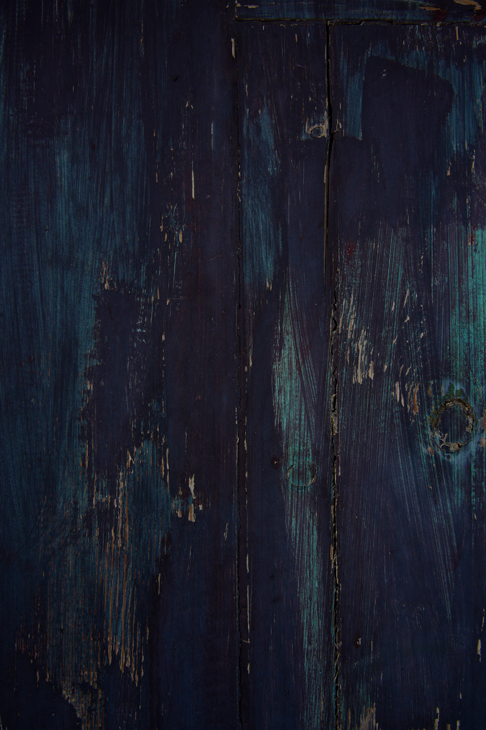 Wood effect vinyl photography backdrop in indigo and near-black tones, with teal tones showing through. Visible brush strokes, scratches and worn patches give it a rustic, painterly and vintage feel. 