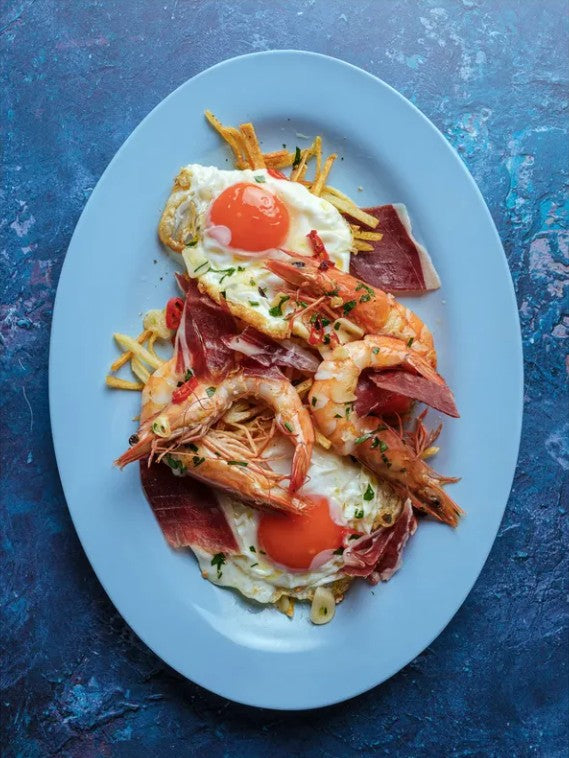 Plated dish with prawns, eggs, and ham on a blue textured food photography background