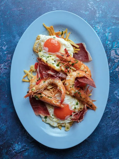 Plated dish with prawns, eggs, and ham on a blue textured food photography background