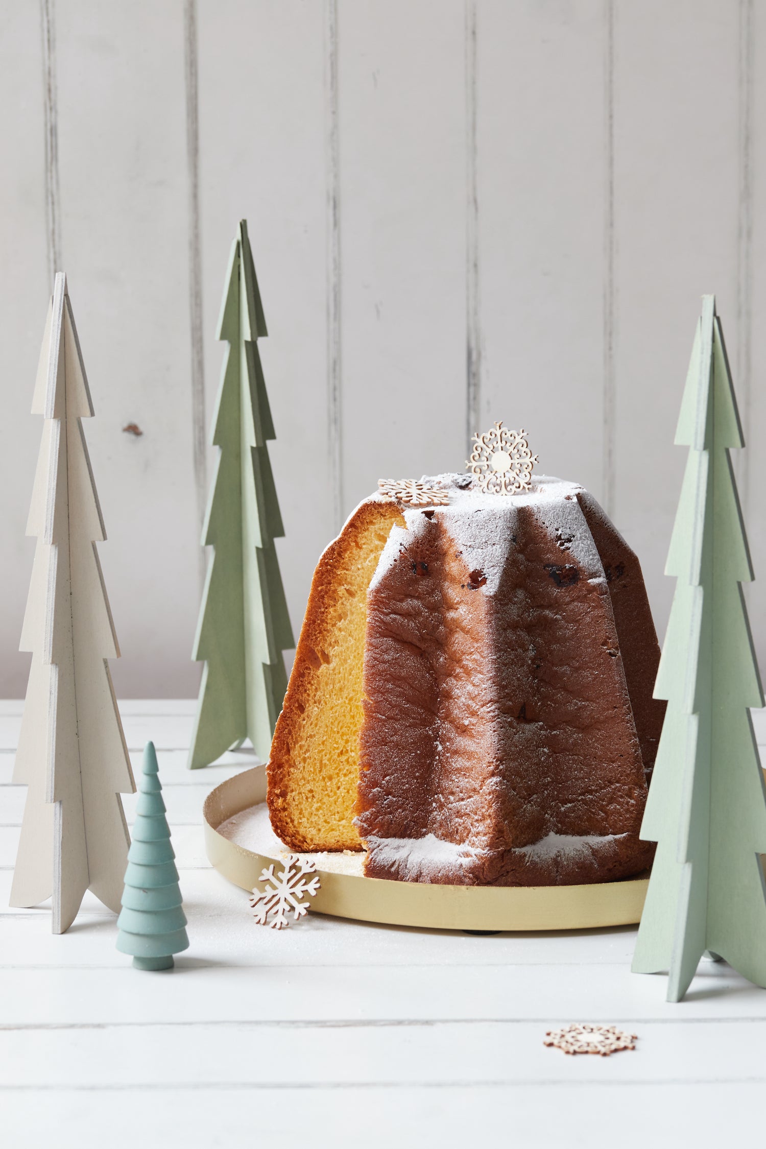 Baked bundt cake with decorative wooden fir trees on a light wood effect vinyl photography backdrop.