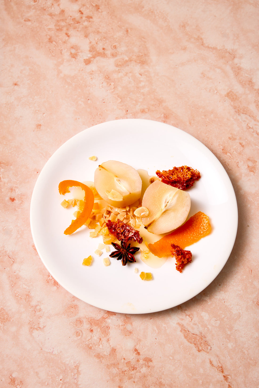 Plate baked fruit on a white plate styled on a pink swirling marble-effect photography backdrop.