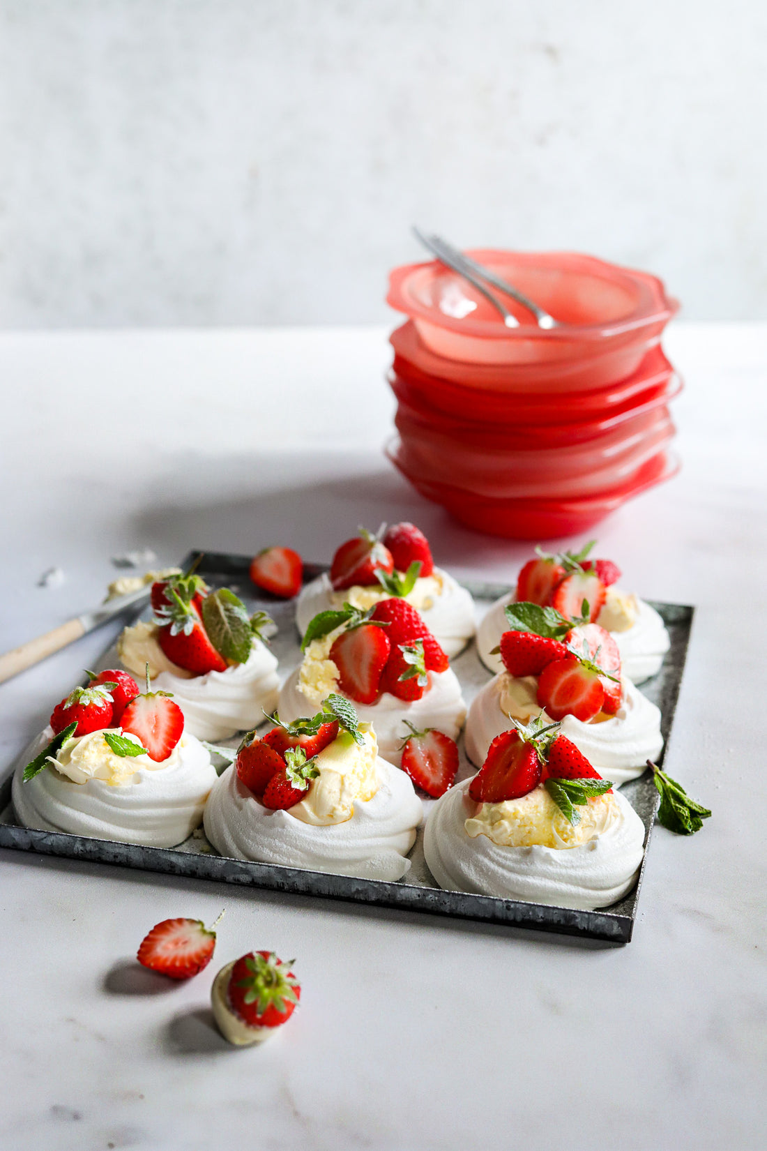 Meringue nests with strawberries styled on a white marble vinyl photography backdrop