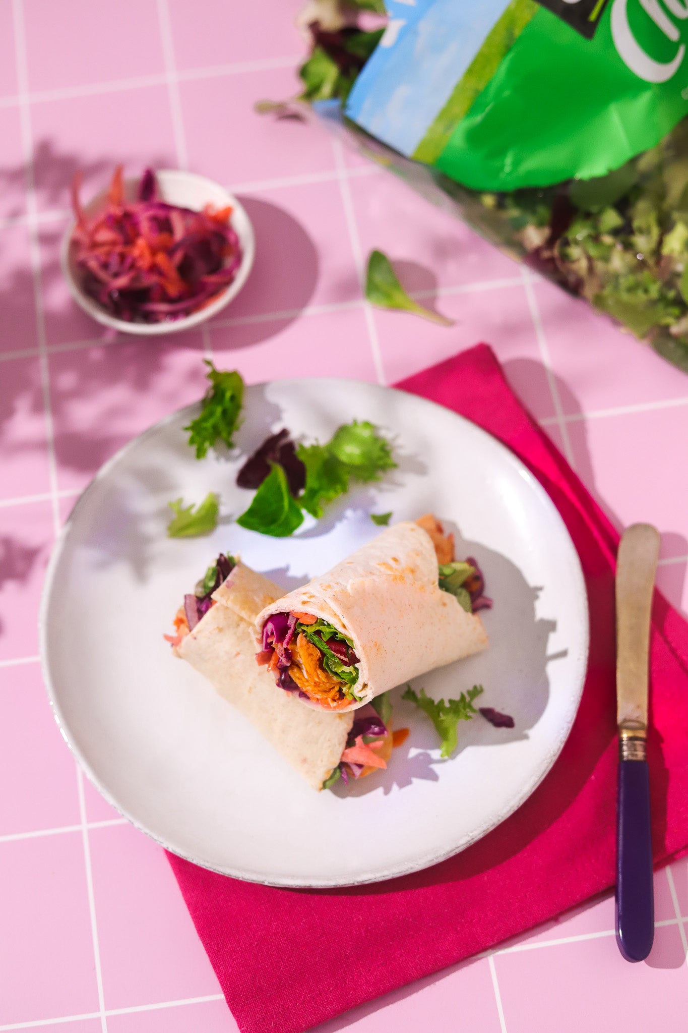 Colourful salad wrap shot on a pink tile graphic effect vinyl photography backdrop for food and product styling.