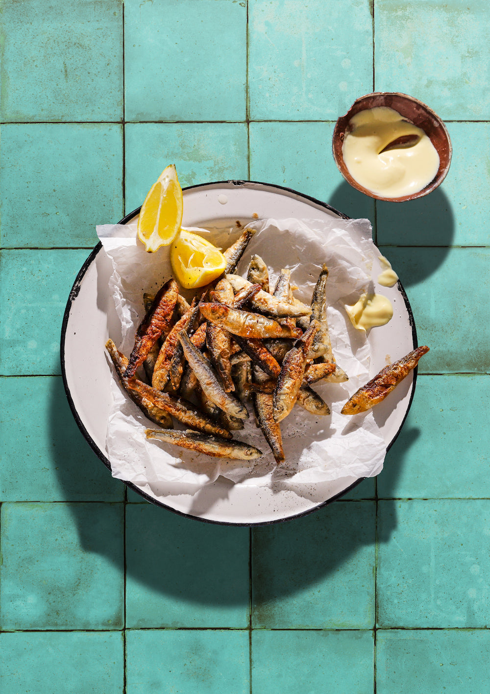 Sardines with lemon and mayo on a aqua tile background