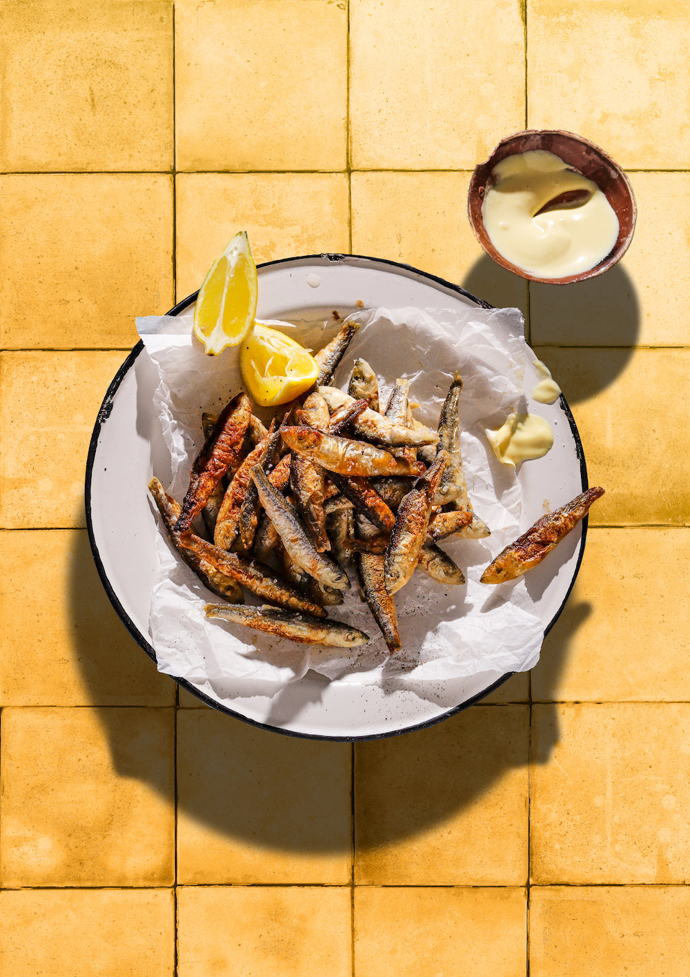 Sardines, lemon and mayo on a yellow tile backdrop