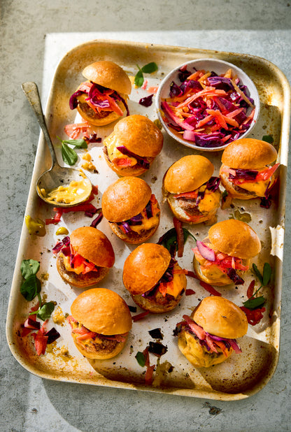 Small burgers on a metal tray with coleslaw