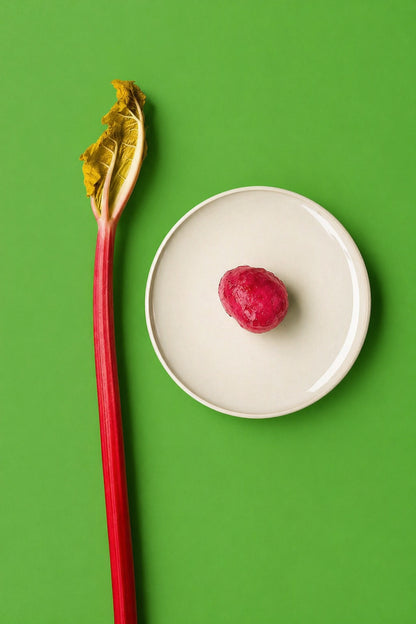 Red rhubarb stalk with pink rhubarb jam on a white plate against a green background