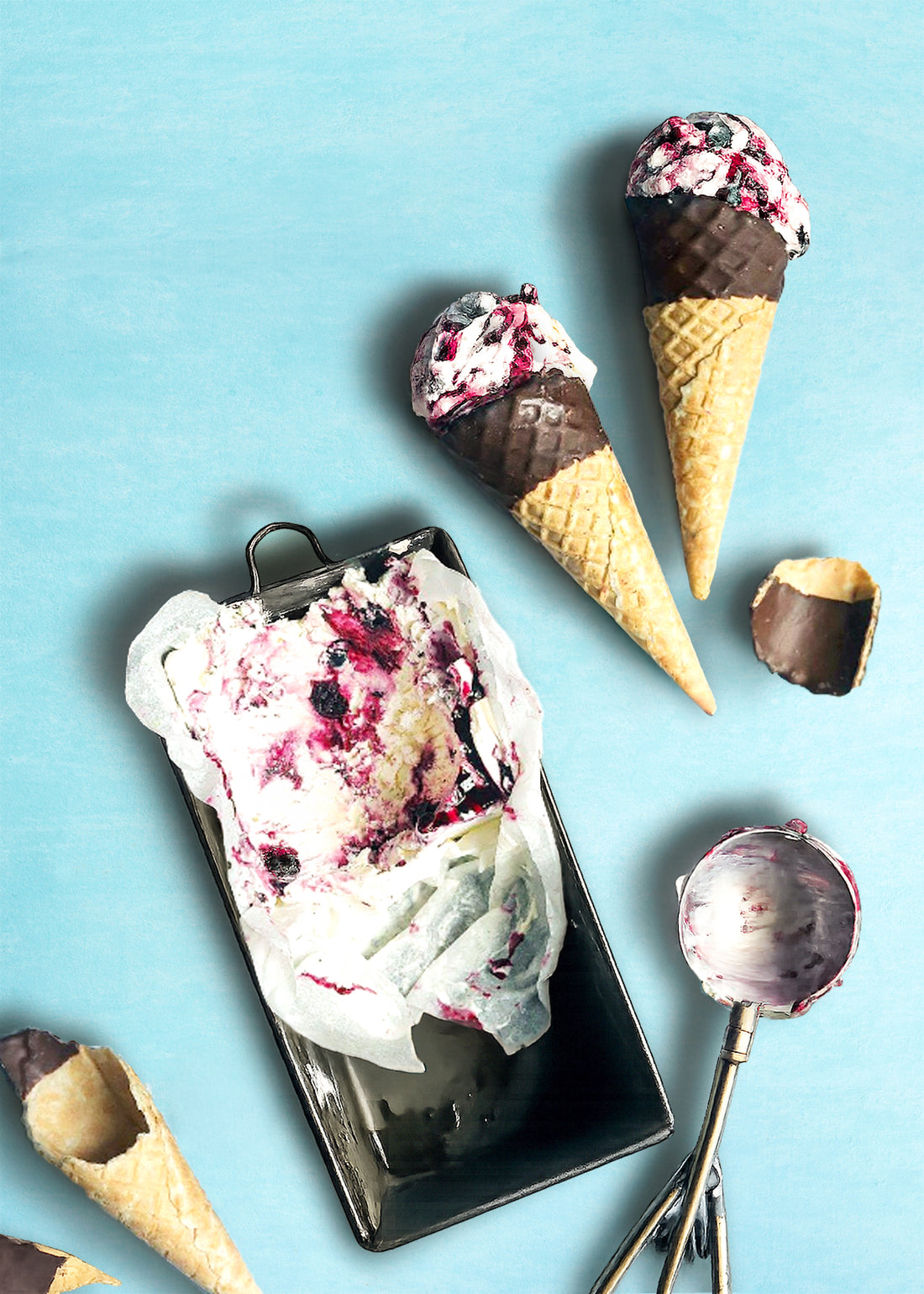 Blueberry ice cream cones and a scoop on a blue background