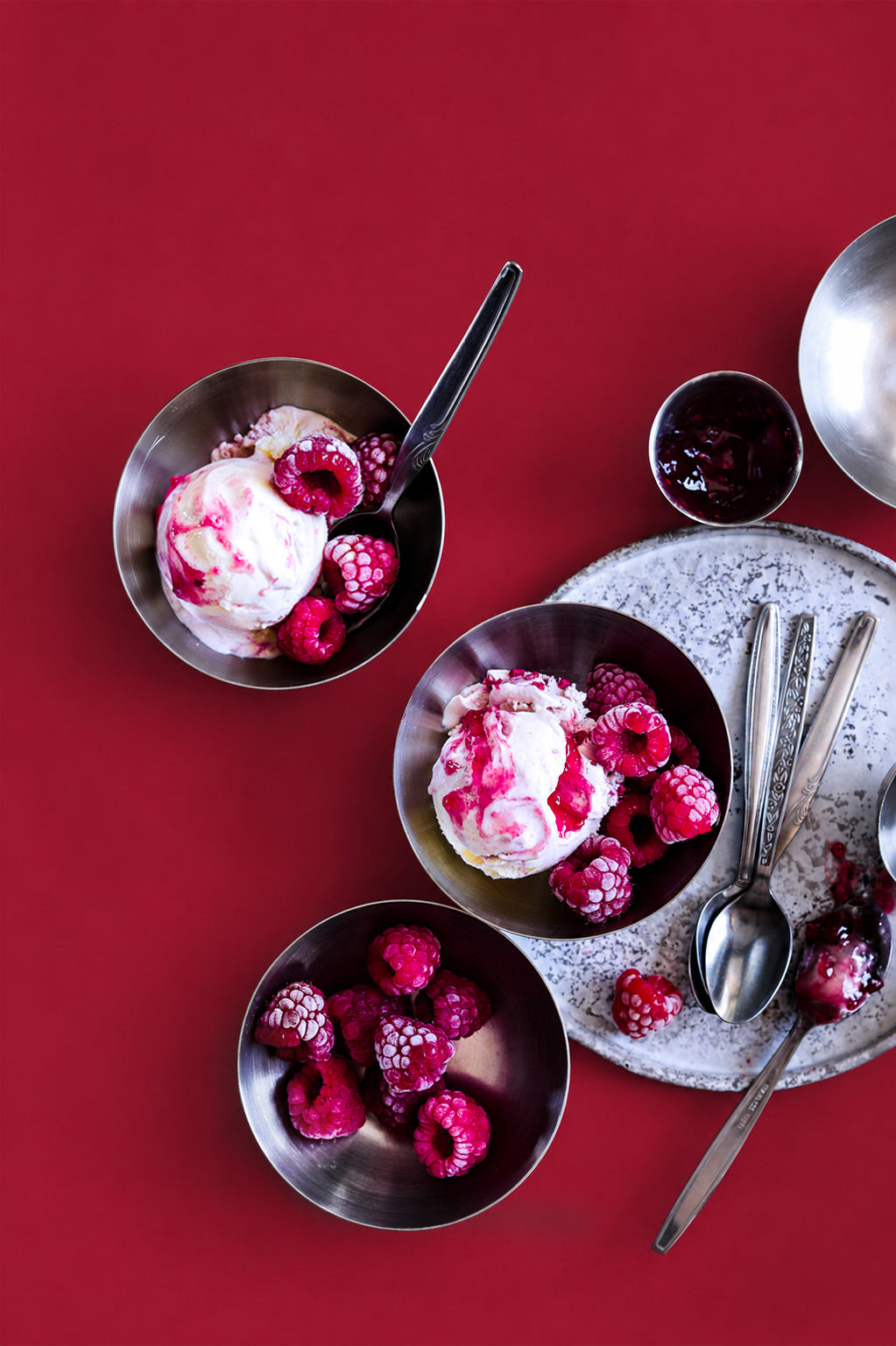 Bowls of ice cream with raspberries on a red background