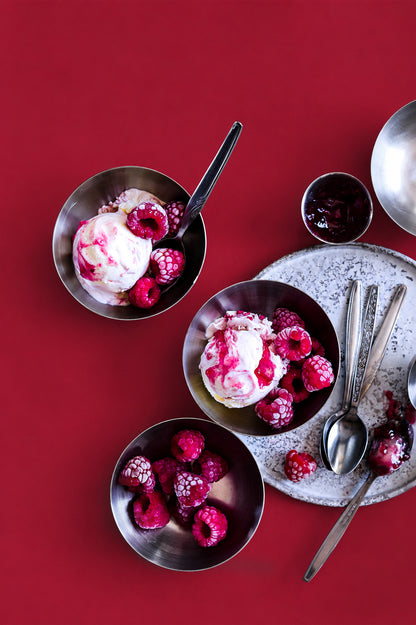 Bowls of ice cream with raspberries on a red background