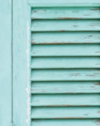 Close-up of a vinyl photography backdrop featuring a pair of blue wooden shutters with a blurred effect.