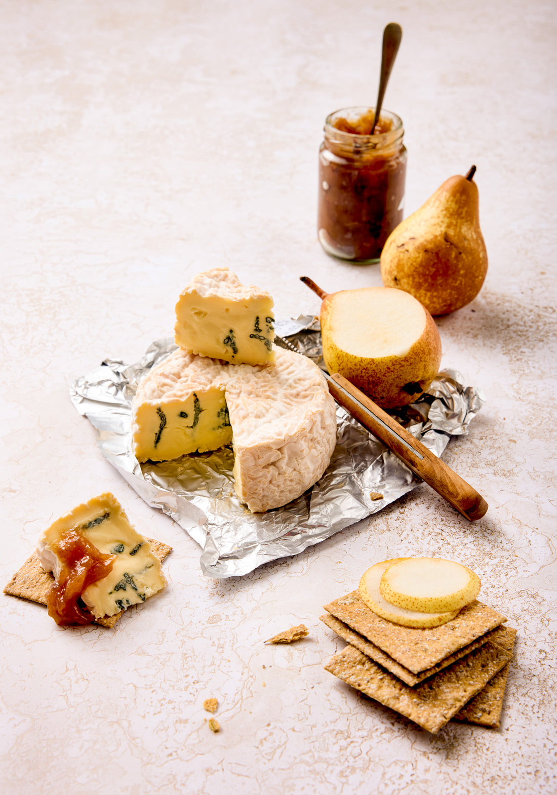 A cheese and chutney spread styled on a crackled cream paint effect vinyl photography backdrop.
