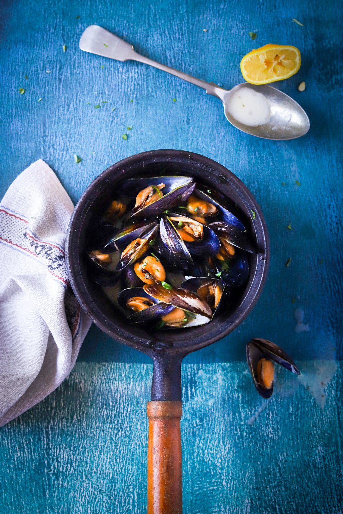 Pan of mussels on a dark and light blue vinyl photography backdrop captured from a handpainted artwork.