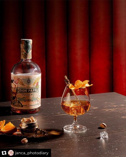 Old fashioned whisky cocktail against a red ribbed leather effect photography backdrop captured from an American diner upholstered booth.